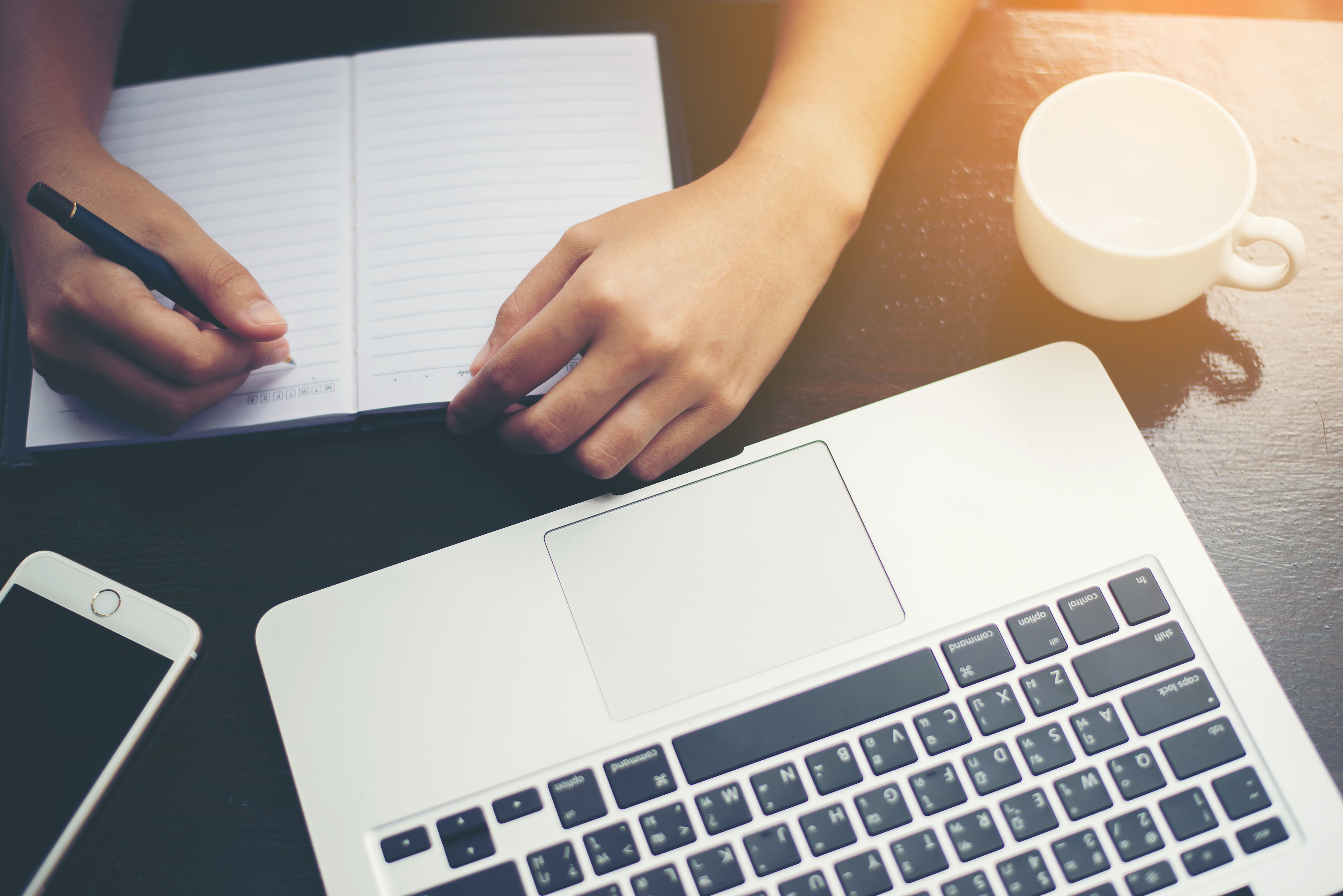 Close-up  of young beautiful woman hands writing and work with laptop computer.